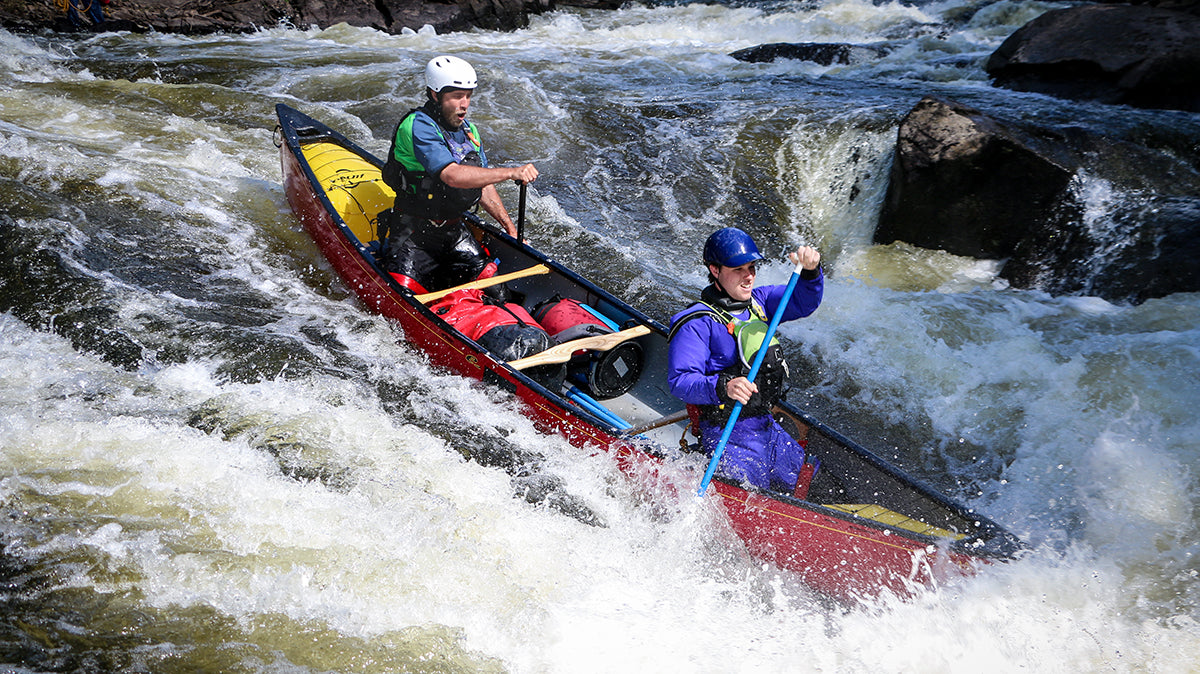 Tandem canoe dropping in through the choppy tongue of the rapids.