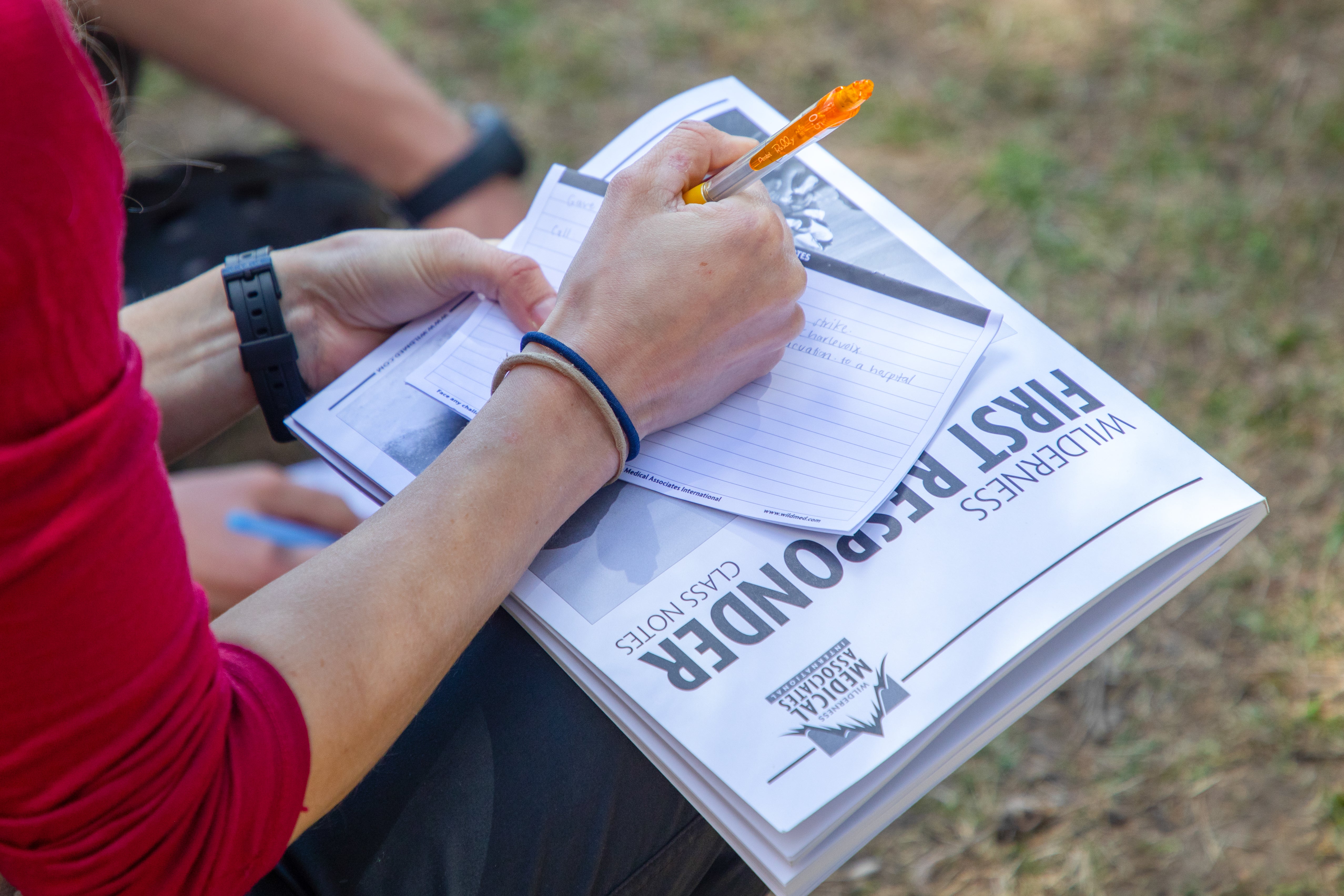 Student taking notes with the provided course material during a wilderness first responder course