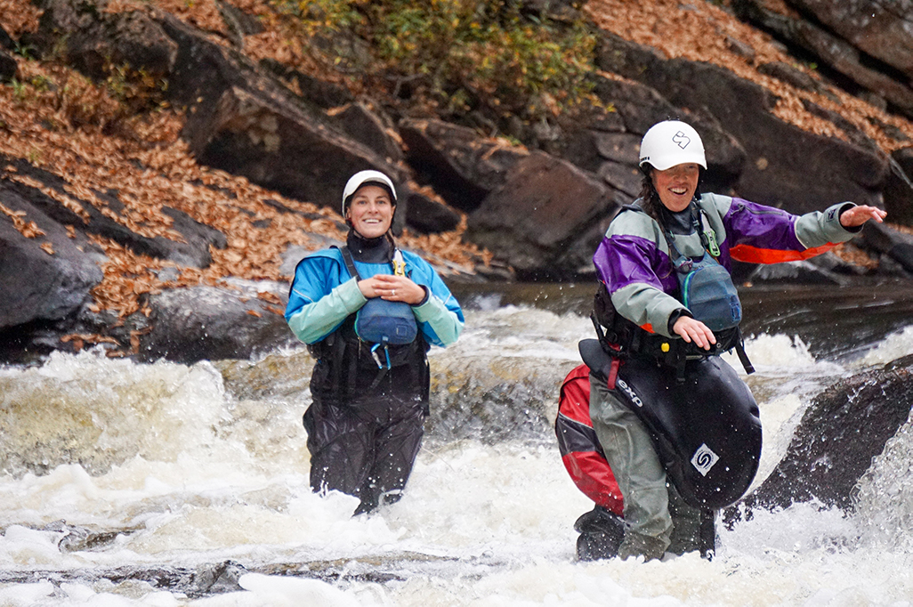 An instructor watches as a student practices their whitewater rescue technique.