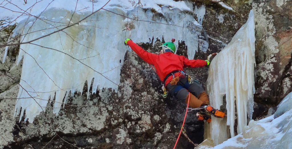 Man ice climbing with rope and picks.
